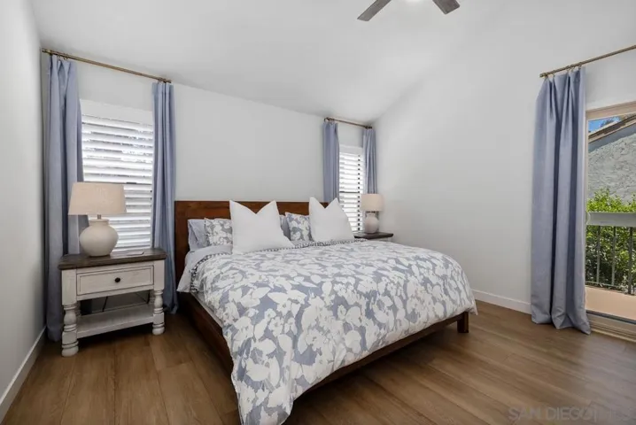 Primary bedroom with vaulted ceiling, plantations shutters, luxury vinyl flooring, ceiling fan, walk-in closet, sliding door to private balcony.