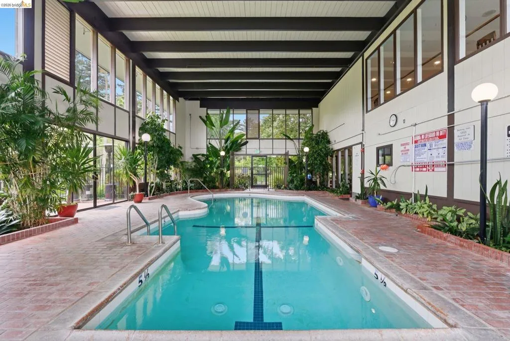Indoor swimming pool with integrated spa, bordered by brick-finish decking