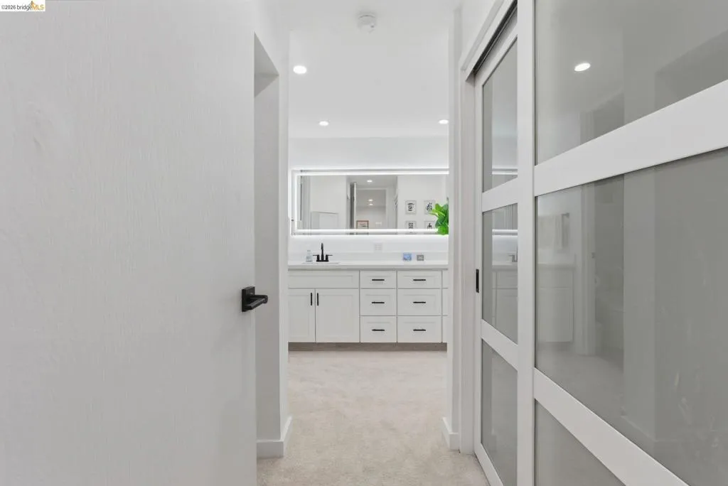 Hallway featuring neutral carpeting and a modern sliding door with frosted glass panels