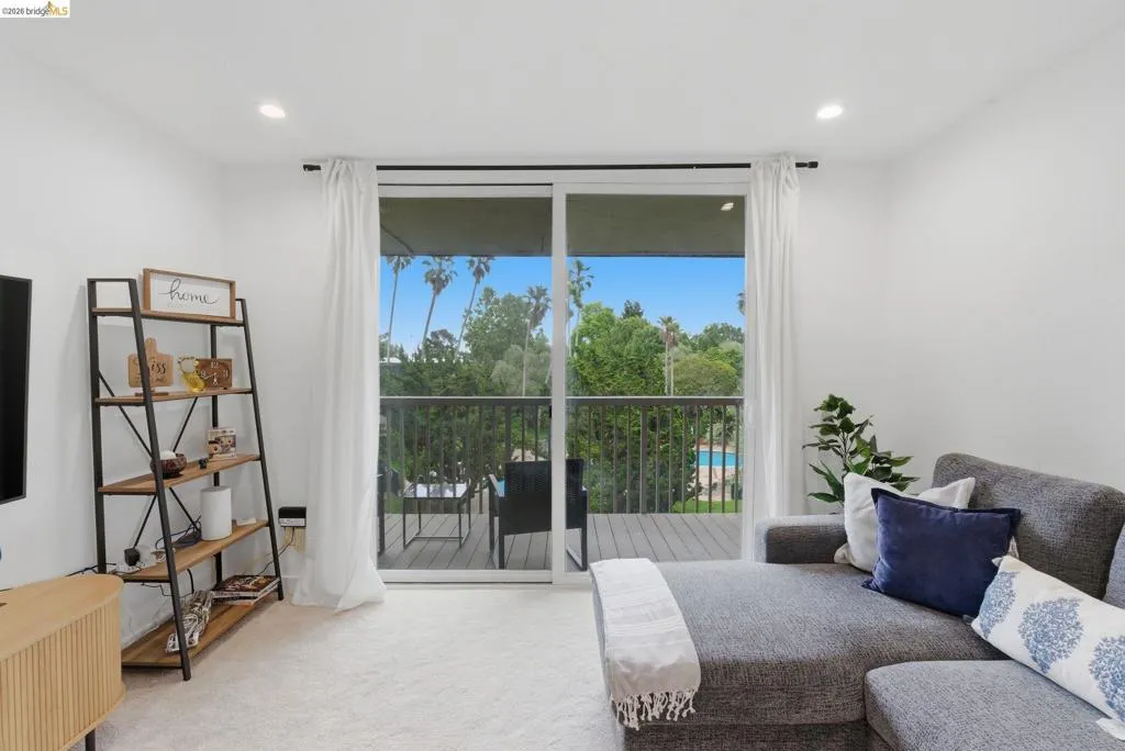 Living area featuring a sliding glass door to an outdoor balcony, recessed lighting, and light-colored carpeting