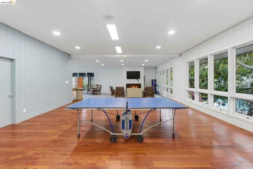 Spacious room featuring wood-finish flooring, a wall of large windows, recessed lighting, and a modern fireplace