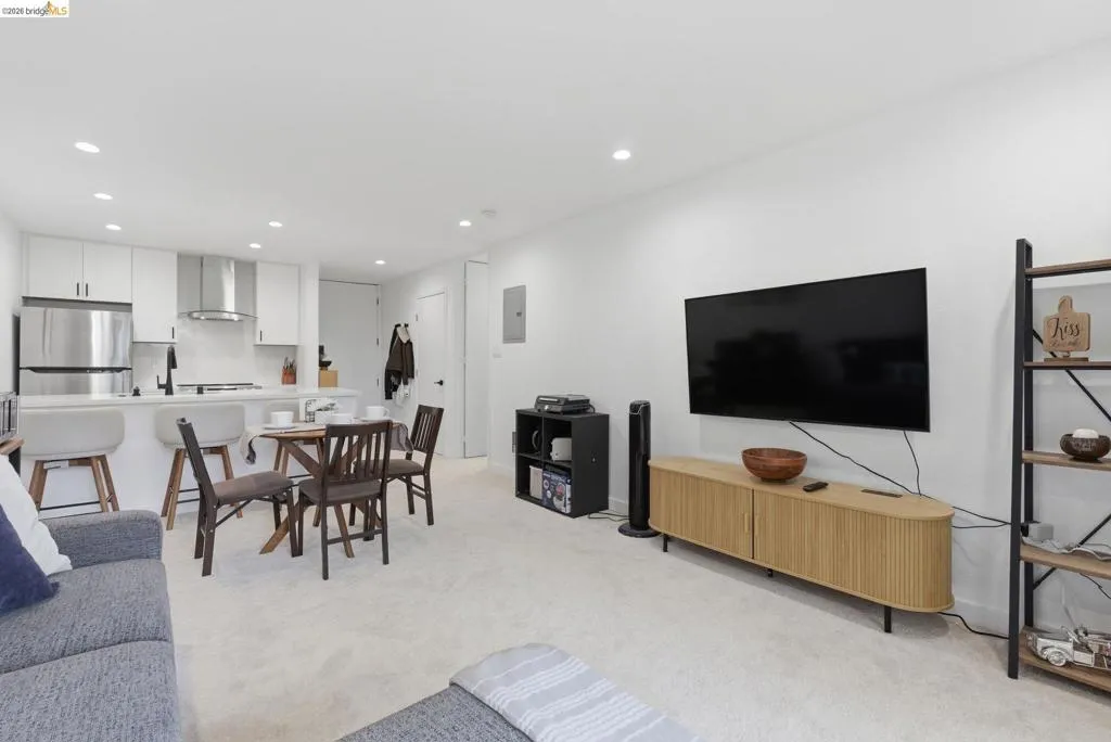 Open-concept living space featuring recessed lighting, white walls, and light-toned carpeting
