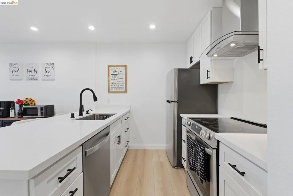 Contemporary kitchen featuring white cabinetry, light-toned wood-finish flooring, and recessed lighting