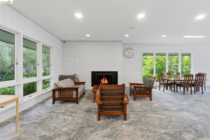 Spacious common area featuring a fireplace with black tile surround, extensive window banks, recessed lighting, and a skylight