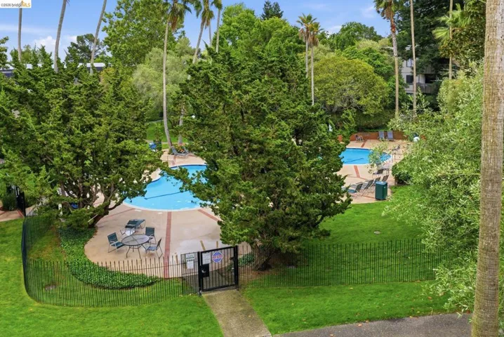 Dual swimming pools with concrete decking, surrounded by mature landscaping and a perimeter fence