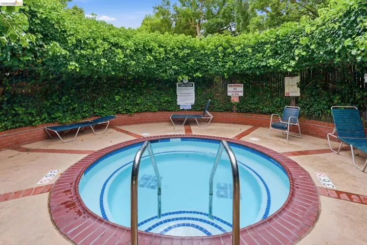 Circular spa featuring a brick coping, blue and white tiled interior, and stainless steel handrails