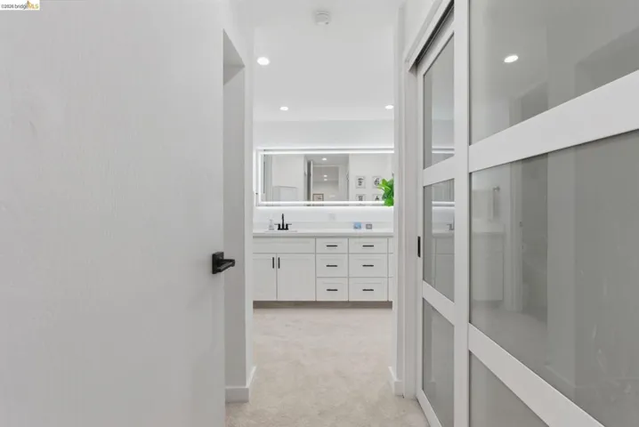 Hallway featuring neutral carpeting and a modern sliding door with frosted glass panels