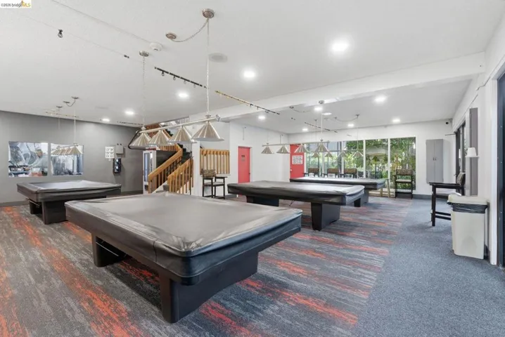 Spacious recreation room featuring multiple billiard tables, recessed lighting, and large windows