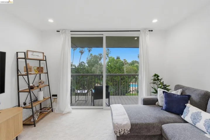 Living area featuring a sliding glass door to an outdoor balcony, recessed lighting, and light-colored carpeting