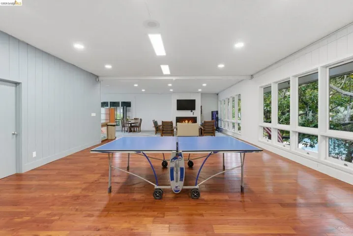 Spacious room featuring wood-finish flooring, a wall of large windows, recessed lighting, and a modern fireplace