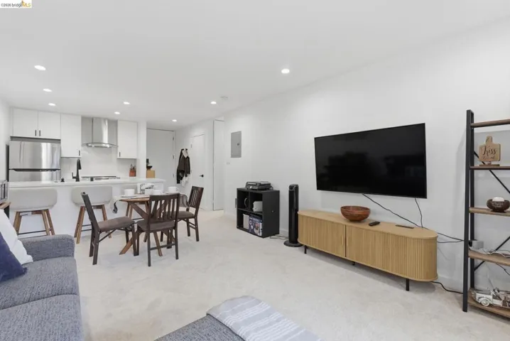 Open-concept living space featuring recessed lighting, white walls, and light-toned carpeting