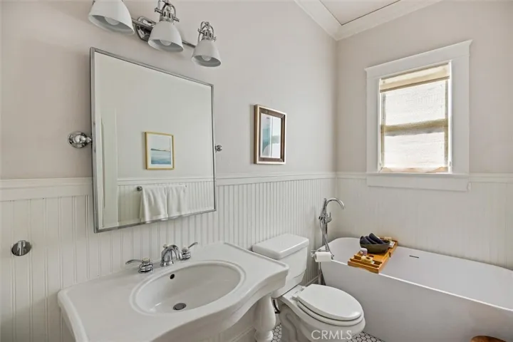 Charming guest bathroom on living level. Complete with hexagon tiles, wainscoting, and soaking tub.