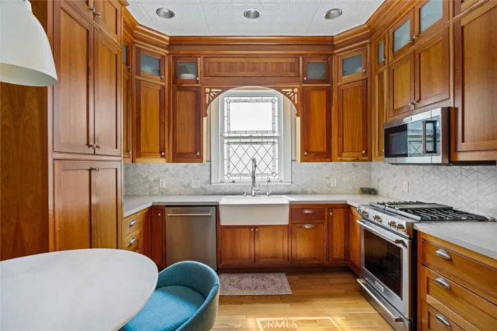 Stunning kitchen with leaded glass window, marble backsplash, farm sink and rich cherry cabinets.