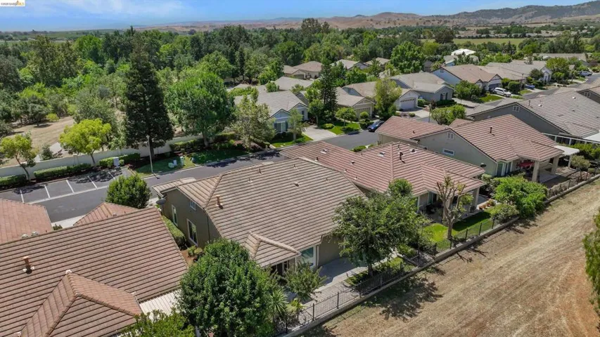 Residential community featuring tile-roof properties, paved roadways, and surrounding mature trees
