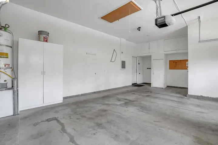 Spacious garage with concrete flooring, overhead storage cabinetry, and a water heater