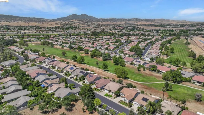 Residential community with a golf course, mature trees, and mountain scenery