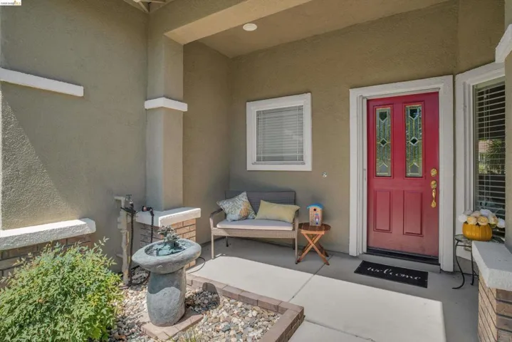 Covered front entry featuring a red door with decorative glass inserts, stucco exterior, and a concrete porch