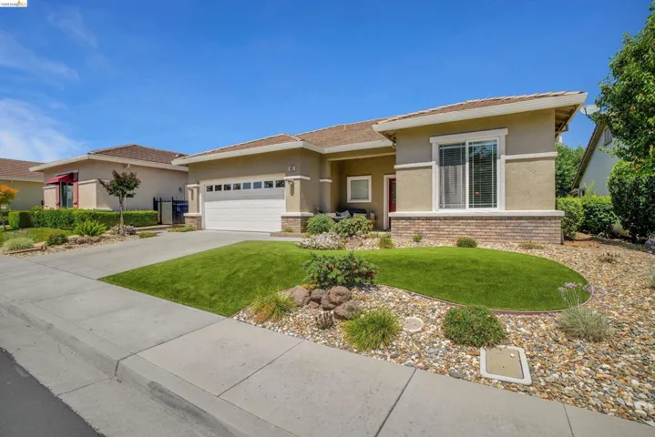 Contemporary single-story residence featuring a two-car garage, low-maintenance landscaping with rock beds, and a manicured front lawn