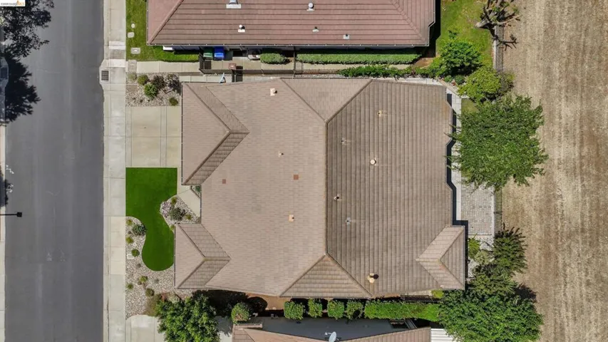 Aerial perspective showcasing a tiled roof, front driveway, and low-maintenance landscaping