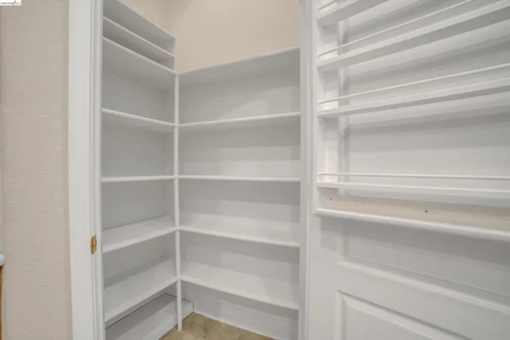 Corner pantry featuring white shelving, multiple storage levels, and a spice rack system on the door