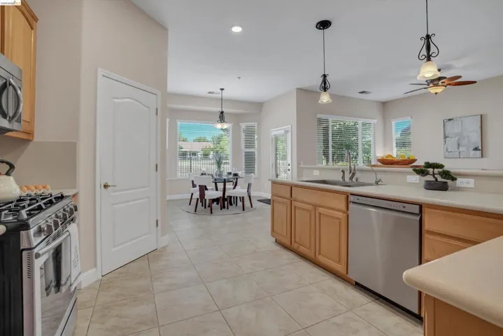 Kitchen with light wood cabinetry, stainless steel appliances, and a tiled floor