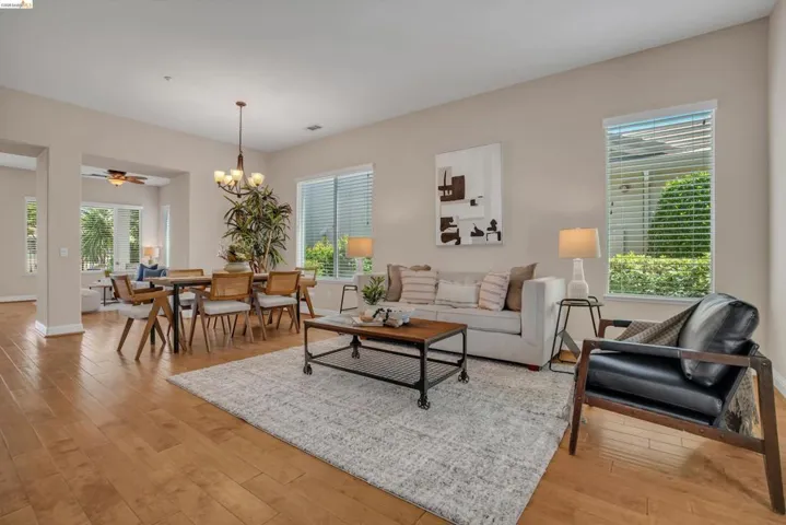Open-concept living area with wood-finish flooring, recessed lighting, and multiple windows with blinds