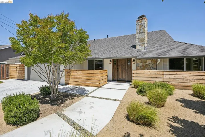 Contemporary exterior showcasing a stone chimney, wood entry door, and a horizontal wood slat fence