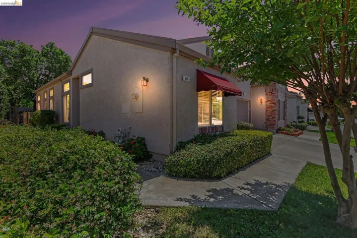 Stucco exterior with a red fabric awning and a prominent bay window