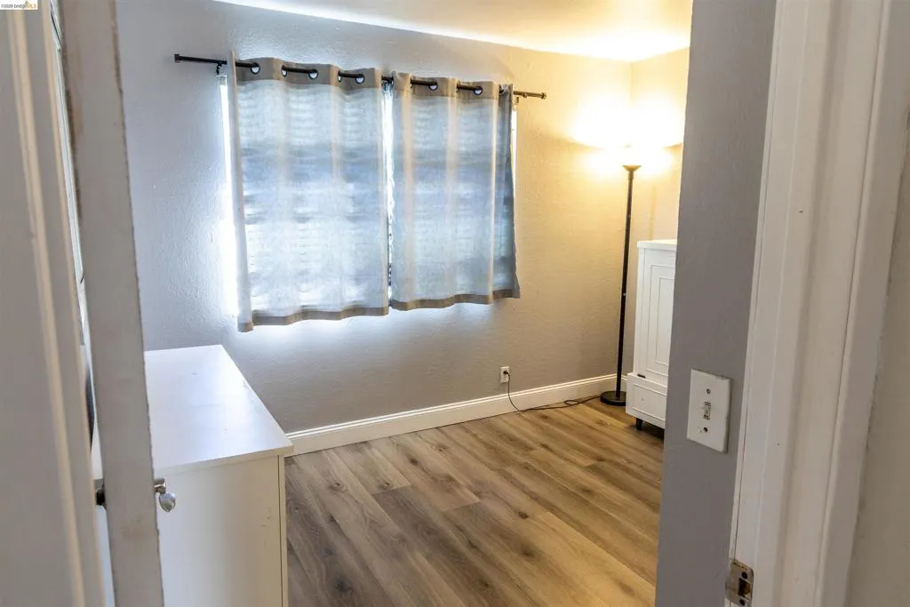 Room featuring wood-finish flooring, light gray wall paint, and white baseboards