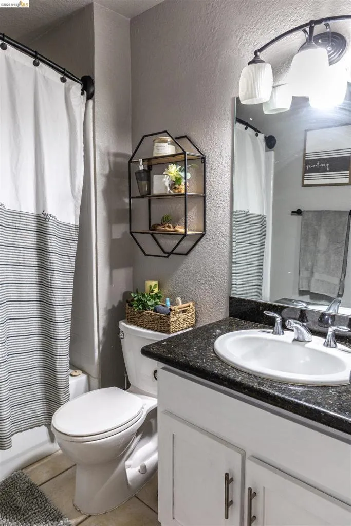 Bathroom featuring a built-in vanity with white cabinetry and dark granite-finish countertop