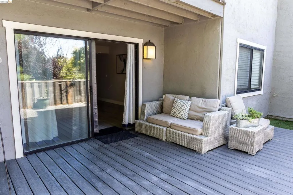 Spacious outdoor deck featuring gray wood-finish decking and a sliding glass door for interior access