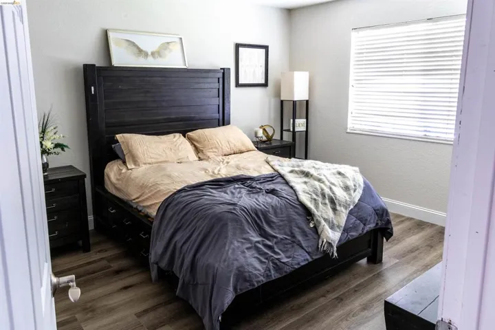Bedroom featuring wood-finish flooring, a window with horizontal blinds, and baseboard molding