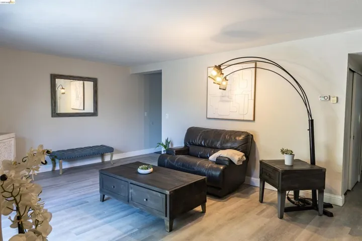 Living area featuring light wood-finish flooring, neutral wall tones, and a built-in thermostat