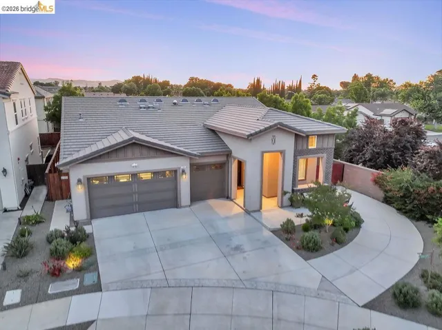 Contemporary-style residence with a neutral stucco and stone facade, featuring a multi-pitched tile roof
