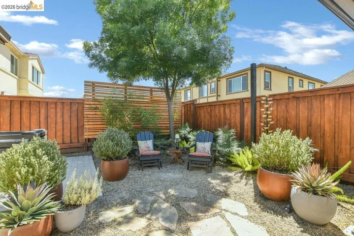 Private backyard featuring a large shade tree, flagstone pathway, and a gravel ground cover