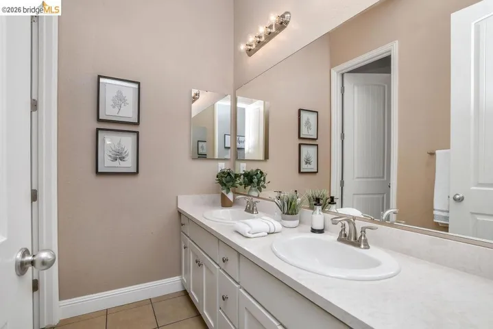 Dual vanity with white cabinetry, brushed nickel hardware, and an expansive countertop