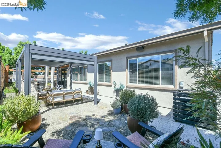 Outdoor living area featuring a modern pergola, stone patio, and gravel landscaping
