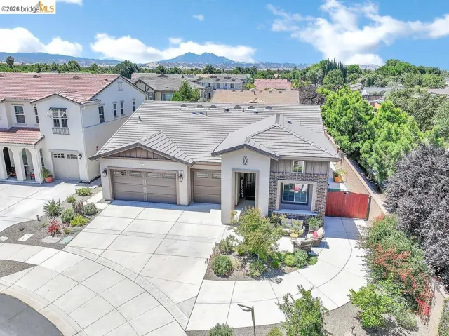Contemporary-style residence featuring a multi-tone tile roof and a tan stucco exterior with stone accents