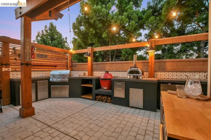 Outdoor kitchen featuring a built-in grill, pizza oven, and extensive counter space with integrated storage