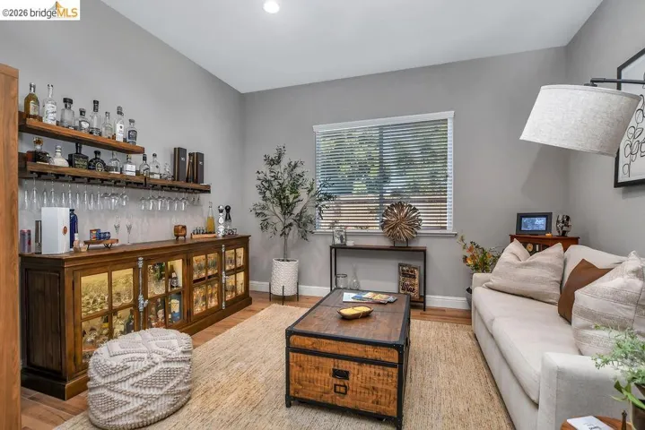 Built-in beverage bar featuring multiple display shelves, integrated cabinetry with glass-front doors, and wood-finish flooring