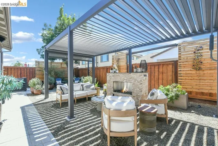 Outdoor living area featuring a louvered pergola over a gravel patio