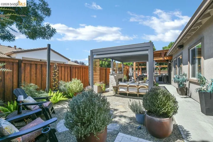 Outdoor living space featuring a modern pergola, stone fireplace, and a concrete patio