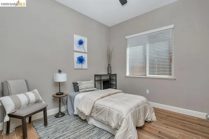 Spacious room featuring wood-finish flooring, a contemporary ceiling fan, and a large window with horizontal blinds