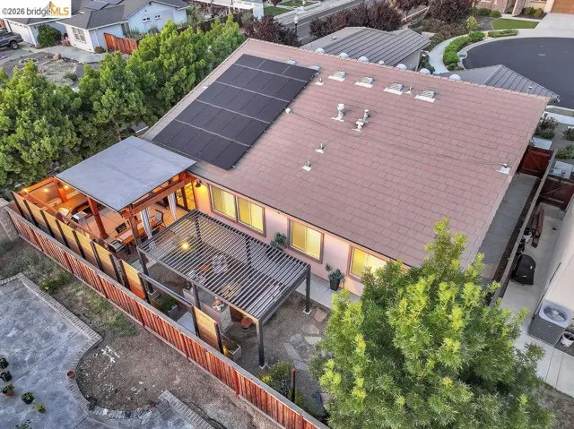 Rear exterior featuring a covered patio, an additional louvered pergola, and solar panels
