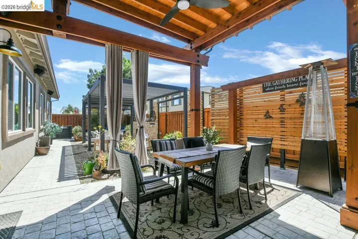 Outdoor living area featuring a wood pergola with a ceiling fan, a patterned patio rug, and a privacy fence
