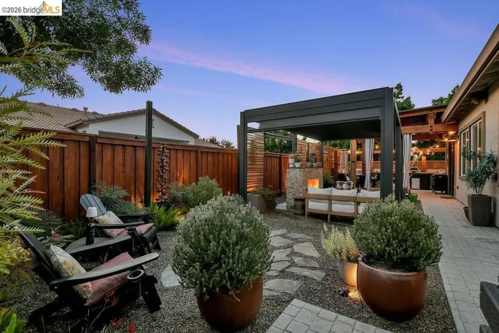 Outdoor living space featuring a modern pergola, stone fireplace, and integrated outdoor kitchen