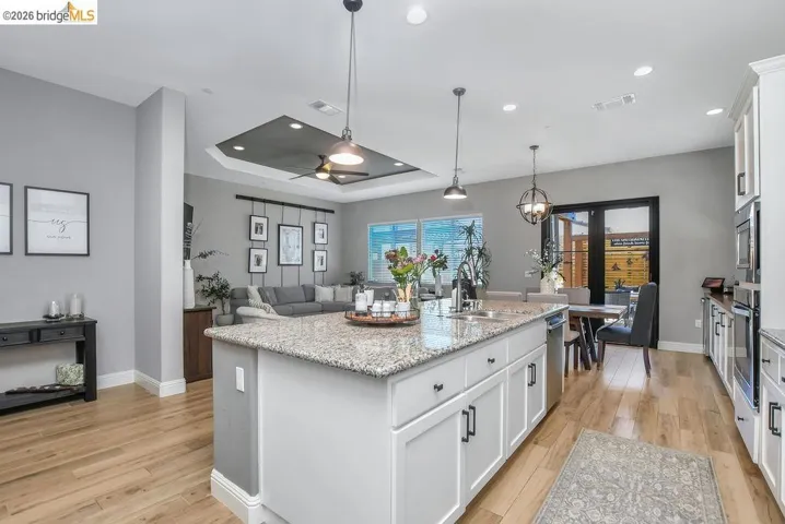 Spacious kitchen featuring a large island with granite-style countertops, white cabinetry, and stainless steel appliances