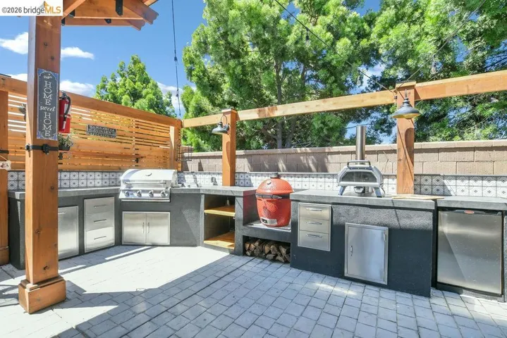 Outdoor kitchen featuring an integrated grill, multiple stainless steel cabinets, and concrete countertops