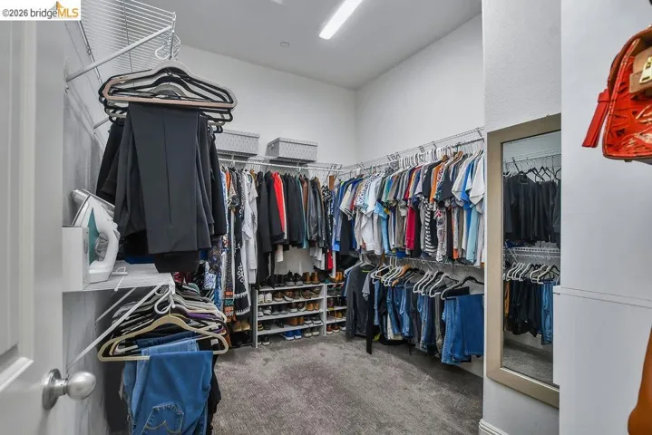 Expansive walk-in closet featuring wire shelving, multiple hanging rods, built-in shoe storage, recessed lighting, and a full-length mirror