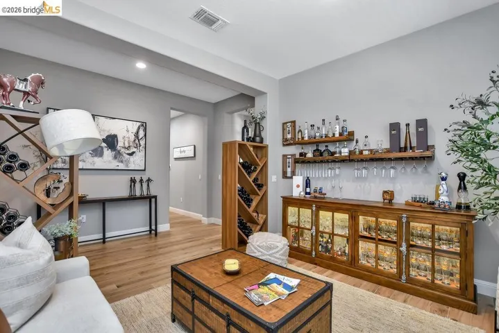 Built-in wet bar with wood-finish cabinetry, illuminated display storage, and integrated glass racks